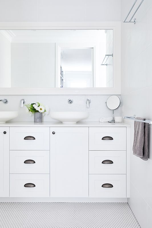 A bathroom with two sinks , a mirror and a towel rack.