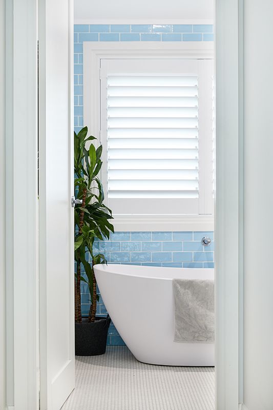 A bathroom with blue tiles and a white bathtub.