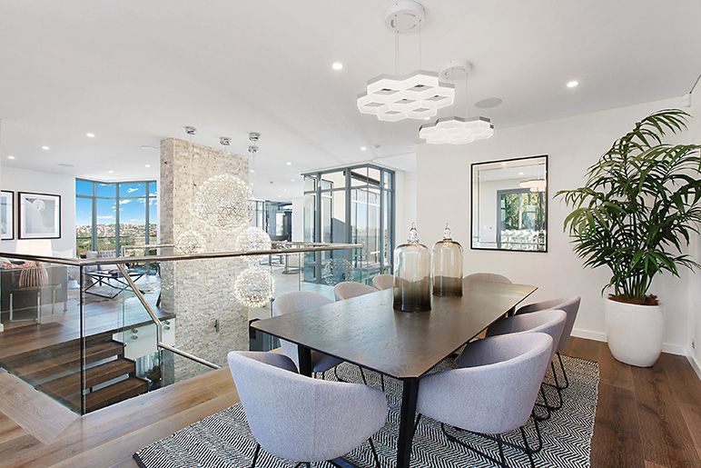 A dining room with a table and chairs and a plant.