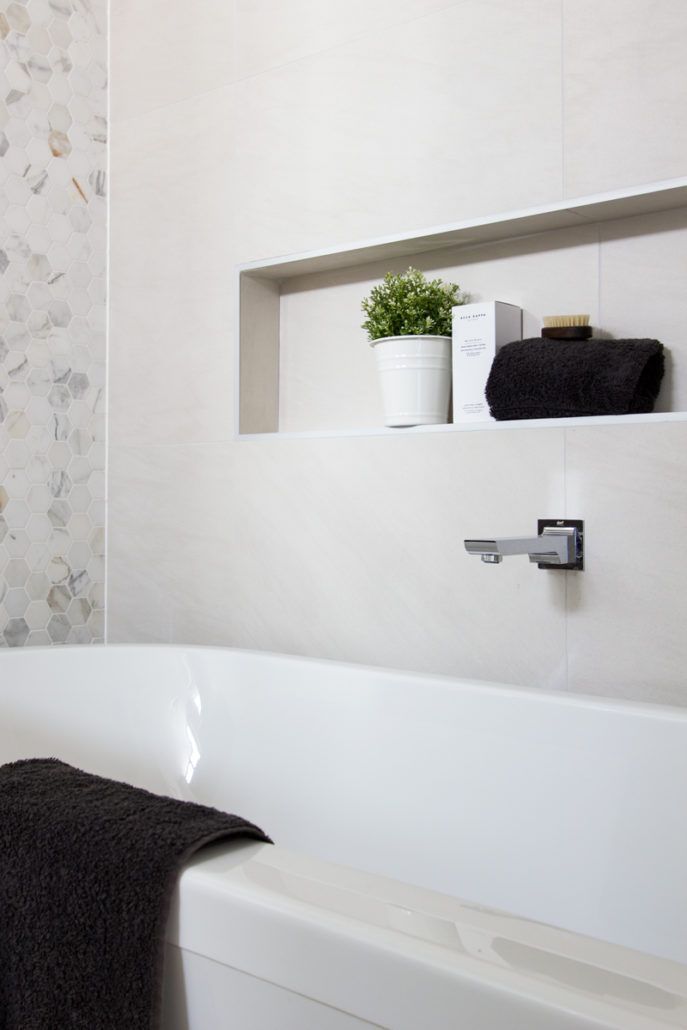 A bathroom with a bathtub and a shelf with towels on it.