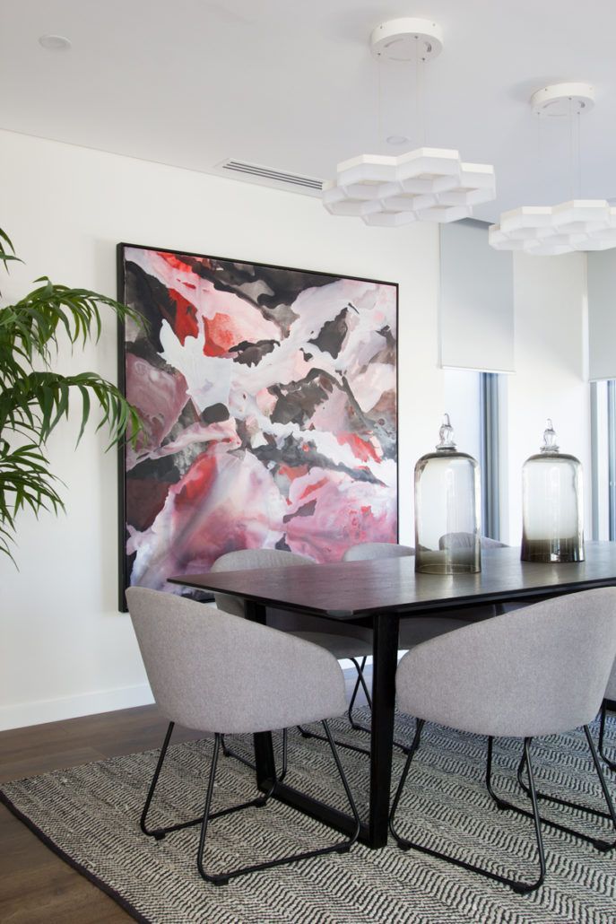 A dining room with a table and chairs and a large painting on the wall.