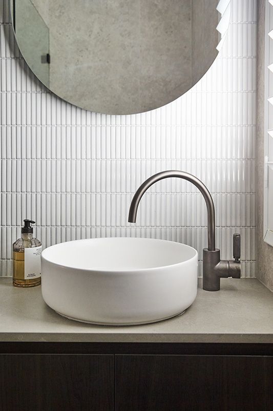 A bathroom with a round sink and a mirror.