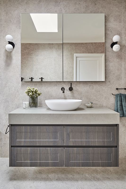 A bathroom with a sink , mirror and drawers.