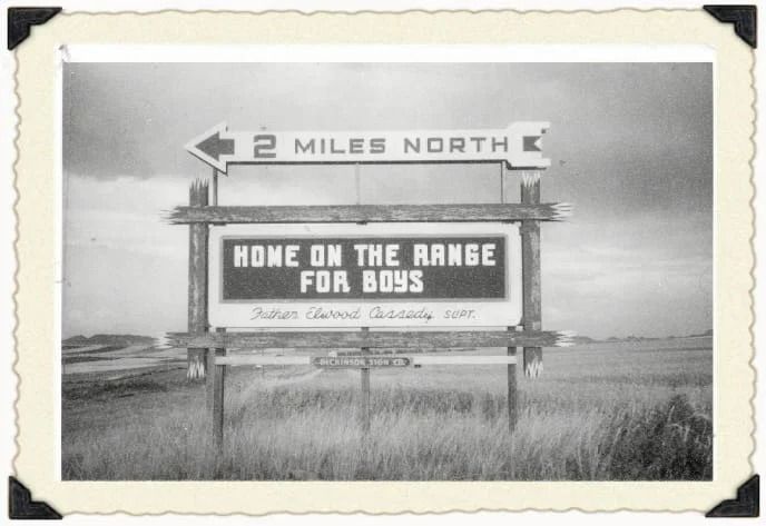 A roadside sign in a rural field reads