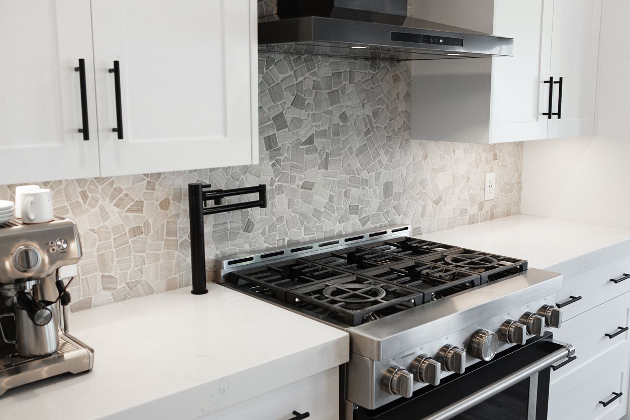 Modern white kitchen with gas range, patterned tile backsplash, and espresso machine on the counter