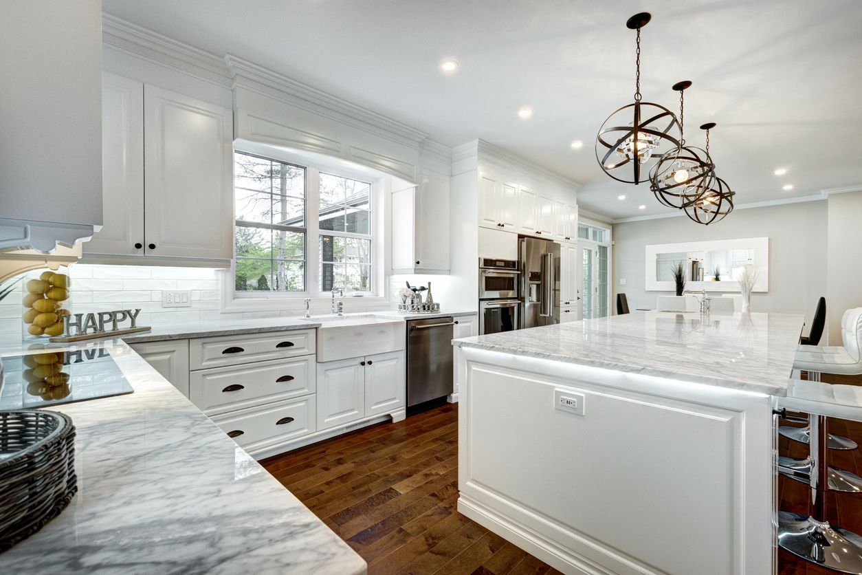 Bright white modern kitchen with marble island, dark wood floors, and hanging pendant lights