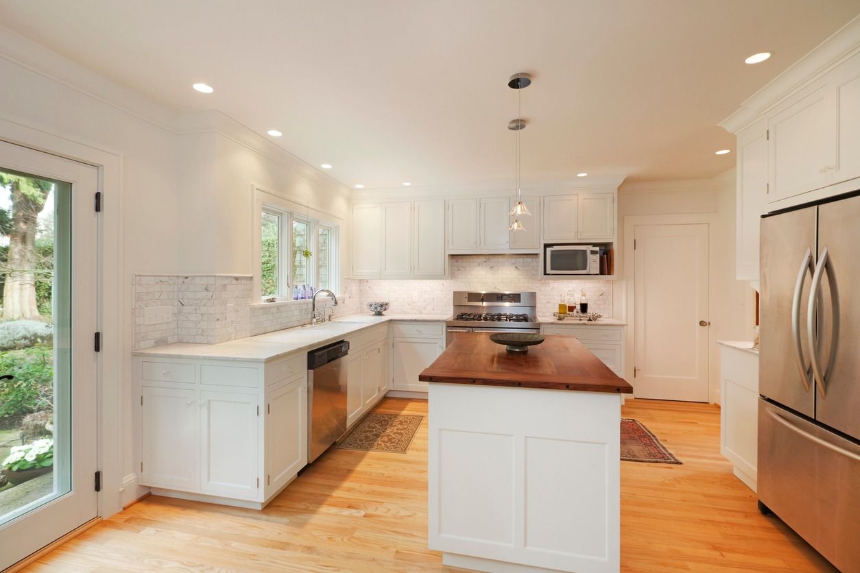 Bright modern kitchen with white cabinets, stainless steel appliances, and a wooden island.