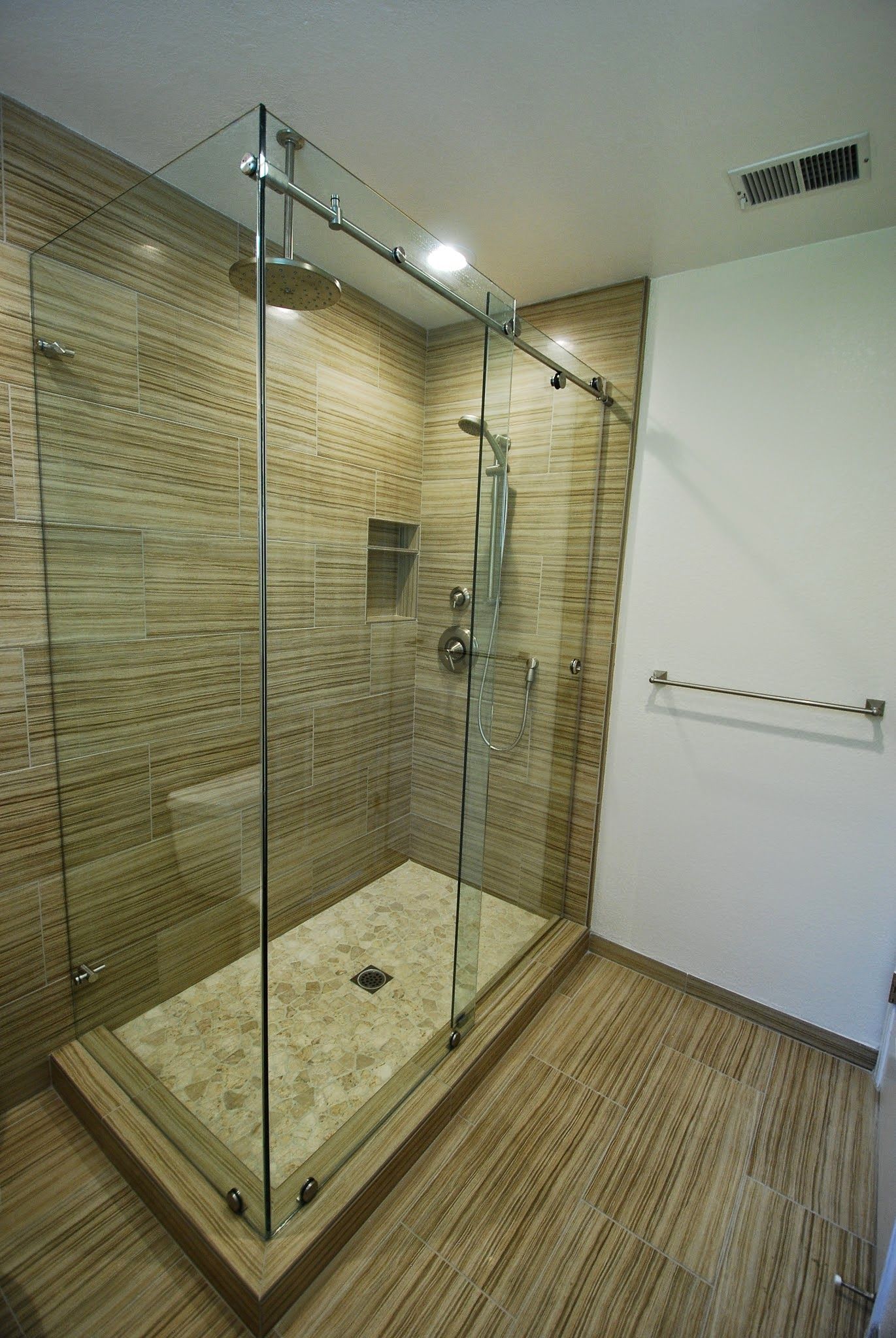 Glass-enclosed tiled shower with beige mosaic walls and floor in a modern bathroom