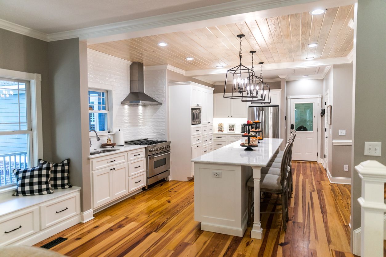 Bright modern kitchen with white cabinets, marble island, pendant lights, and hardwood floors