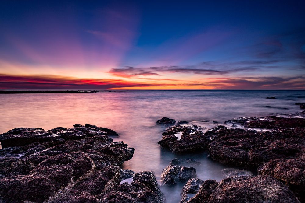 A Sunset Over the Ocean With Rocks in the Foreground — Darwin Caravan & RV Centre In Lee Point, NT