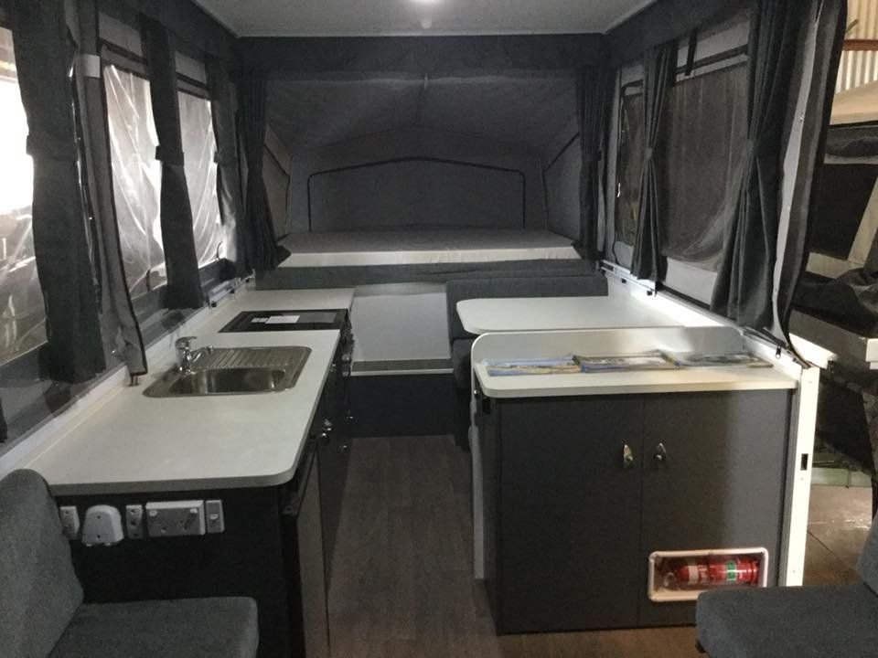 Interior view of a pop-up camper with a bed, kitchen, and seating — Darwin Caravan & RV Centre In Berrimah, NT