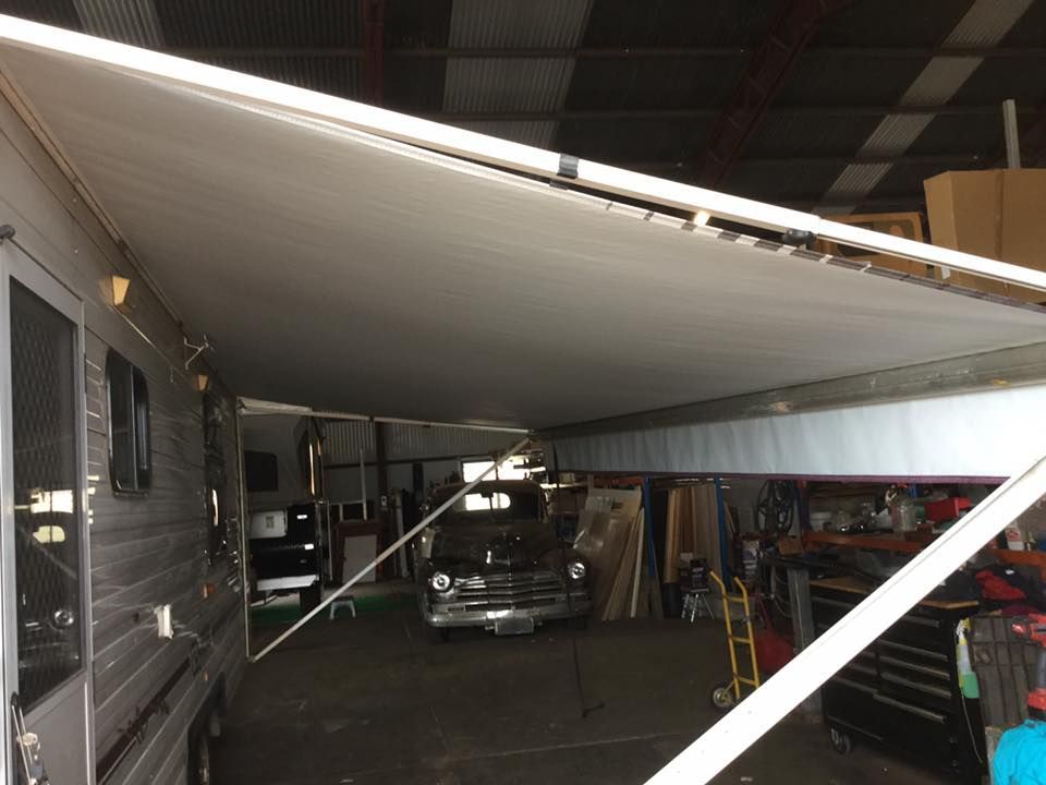 RV with extended awning in a garage, covering a car  — Darwin Caravan & RV Centre In Palmerston, NT