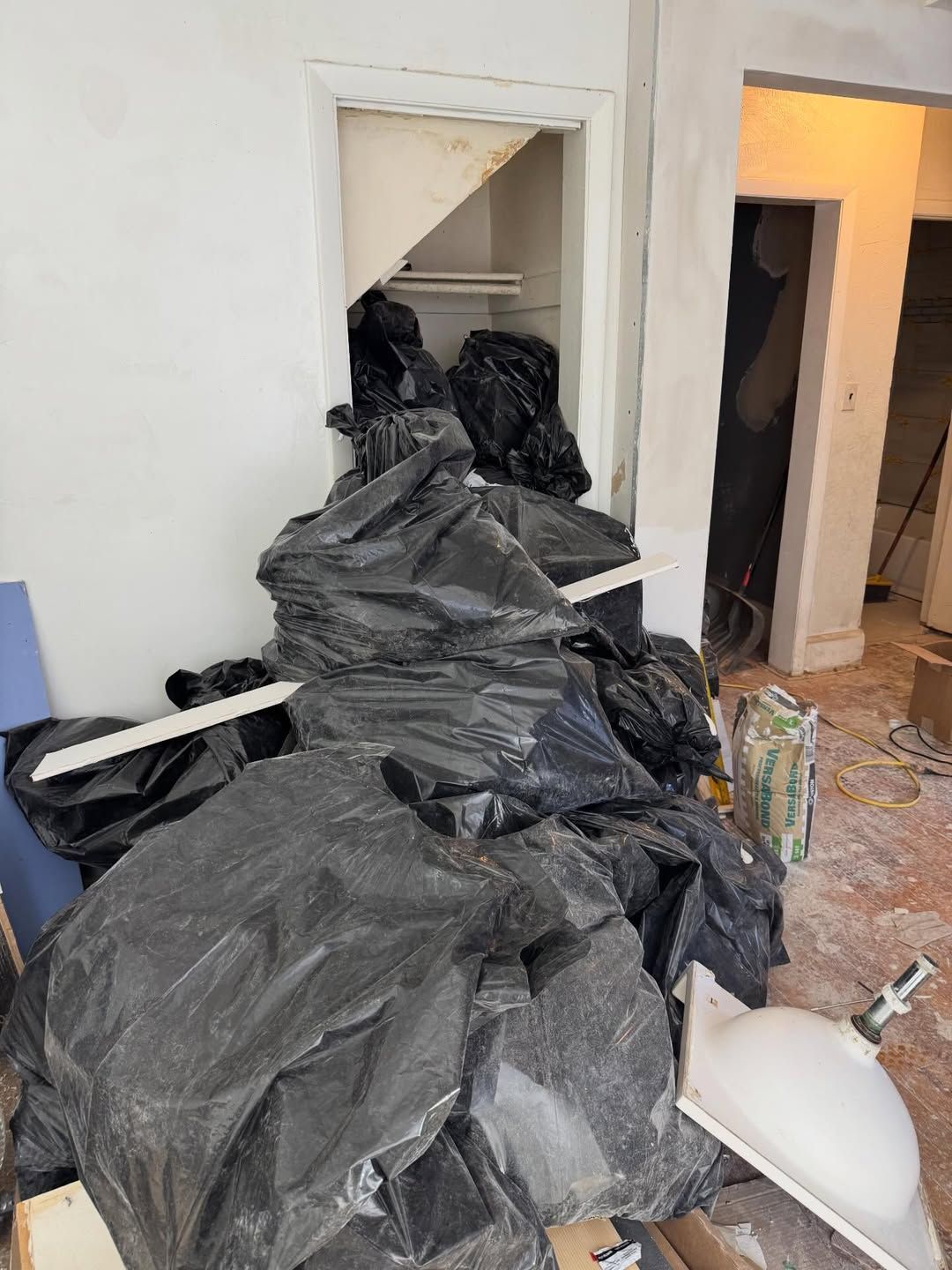 Several cardboard boxes and large contractor bags loaded with trash piled up inside a client's home ready for removal.