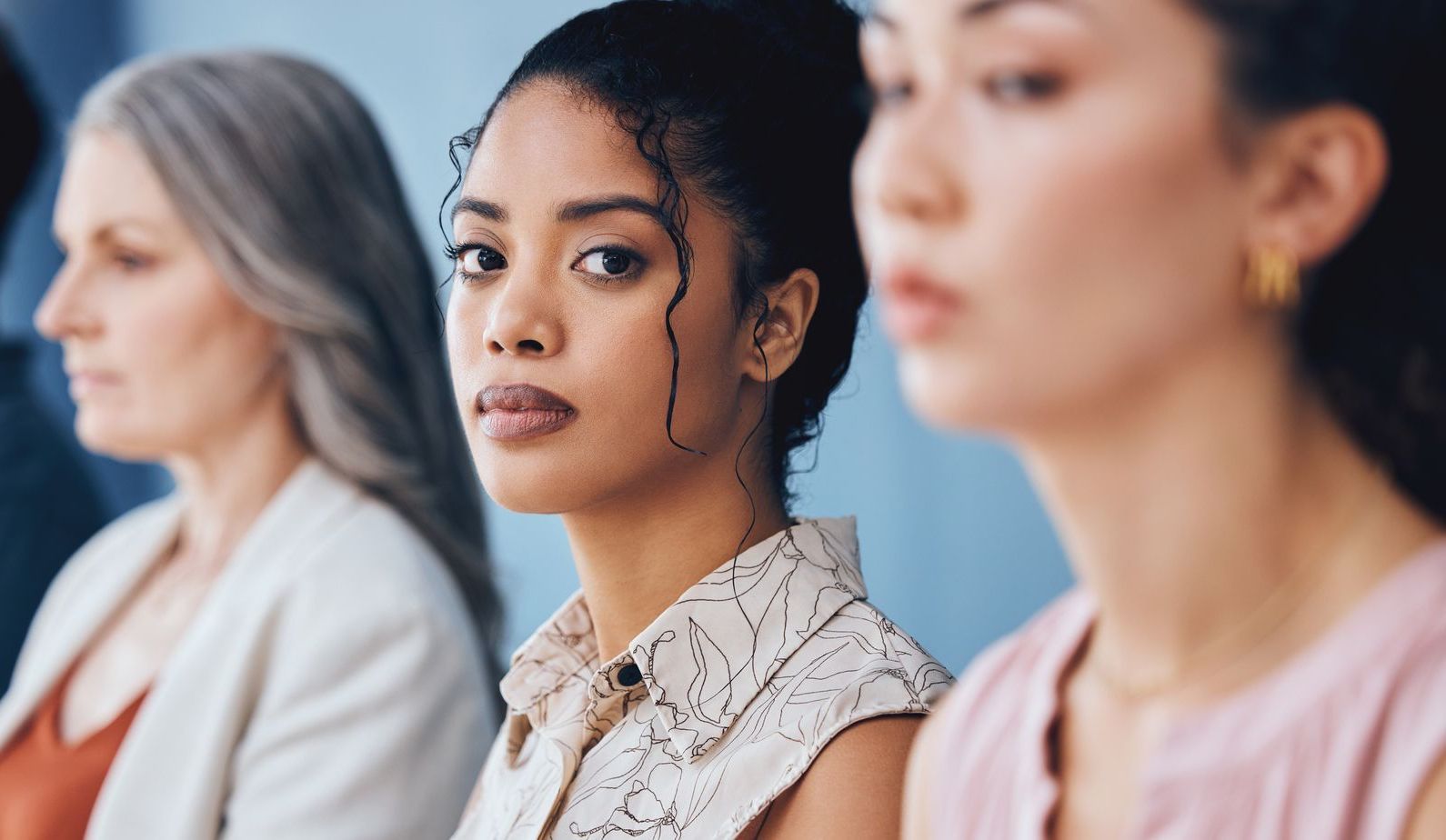 Three women are sitting next to each other and looking at the camera.