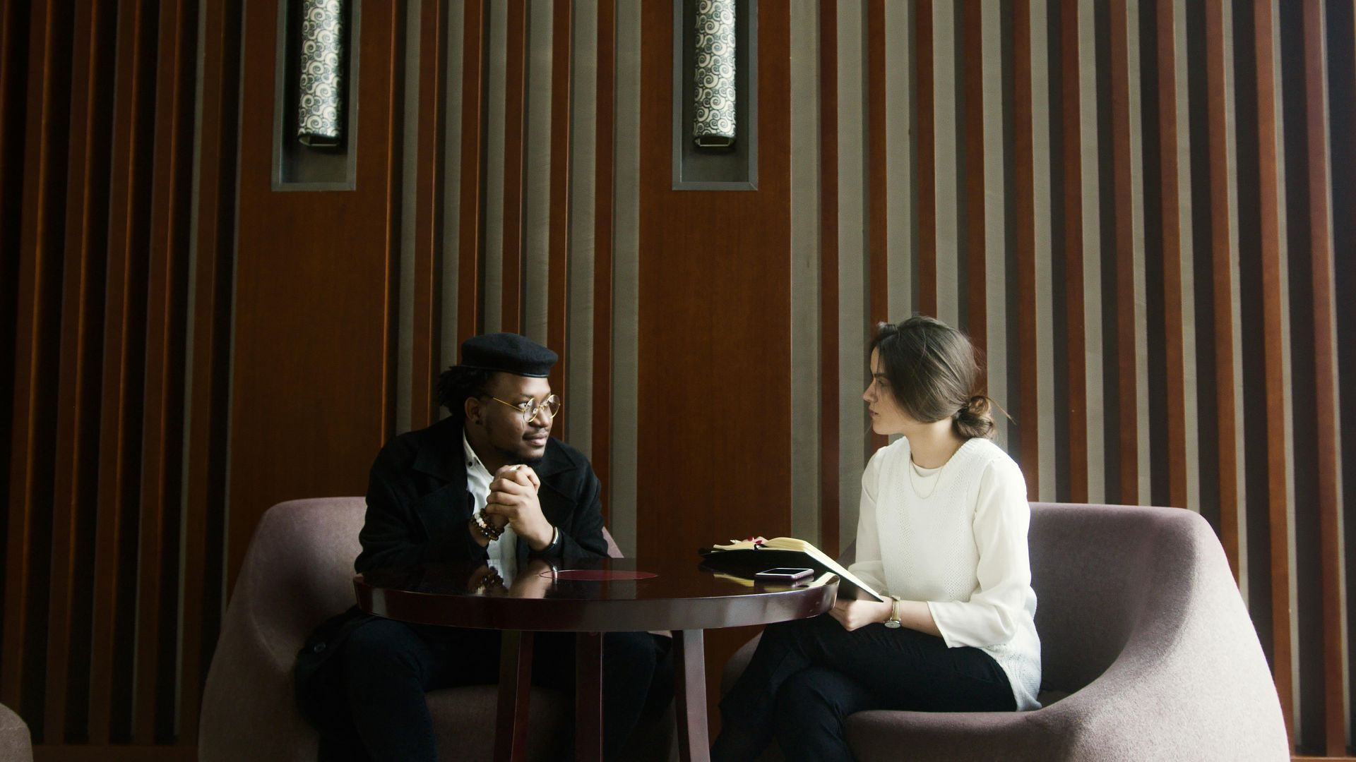 A man and a woman are sitting at a table talking to each other.