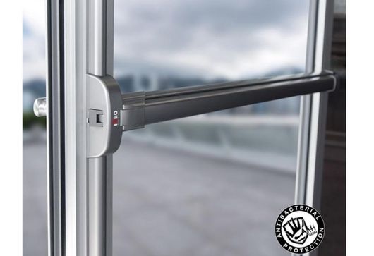 Close-up of a metal window handle on a glass door, with blurred outdoor background.