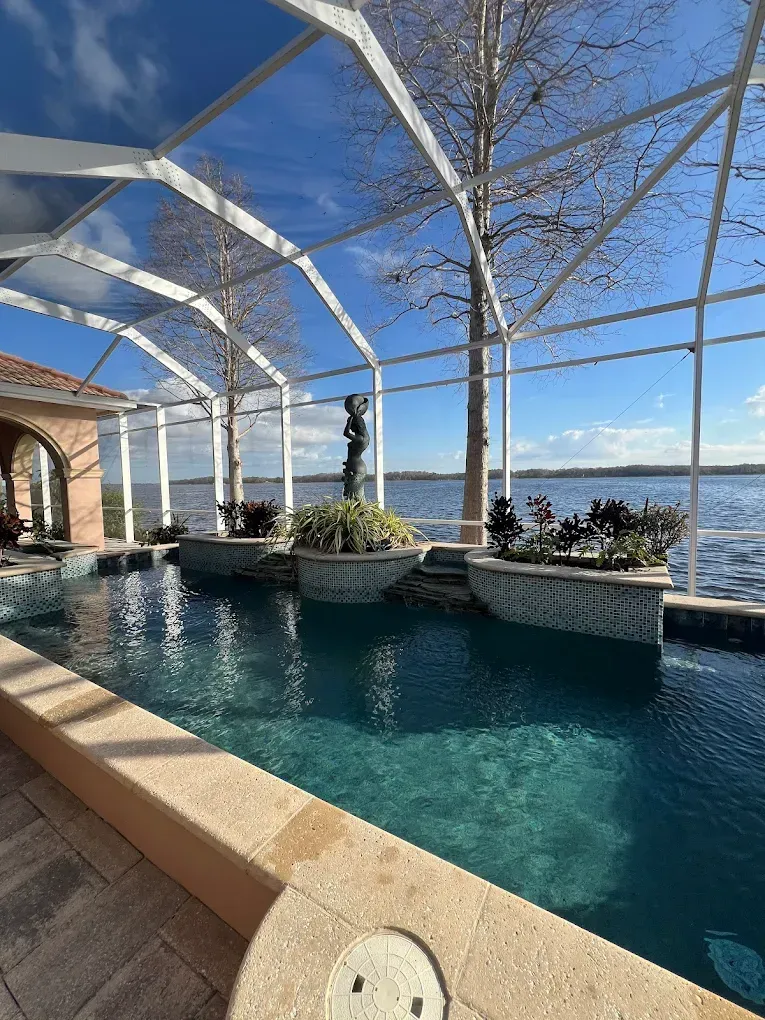 Covered pool overlooking the ocean with a white canopy, blue water, and stone planters.