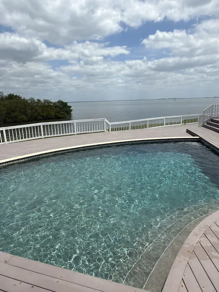 Infinity pool overlooking calm ocean under a cloudy sky