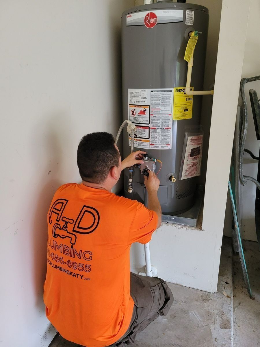 Technician inspecting a water heater in a wall alcove, wearing an orange shirt.