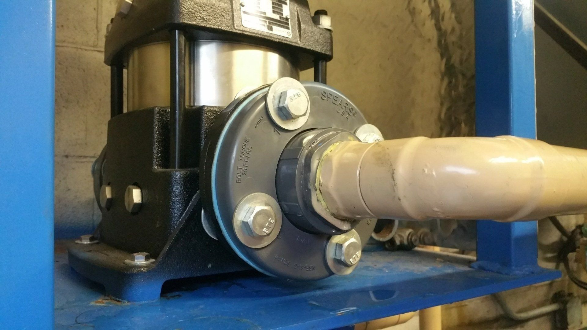 Industrial pump with a white pipe connected to a blue metal base and black motor housing.