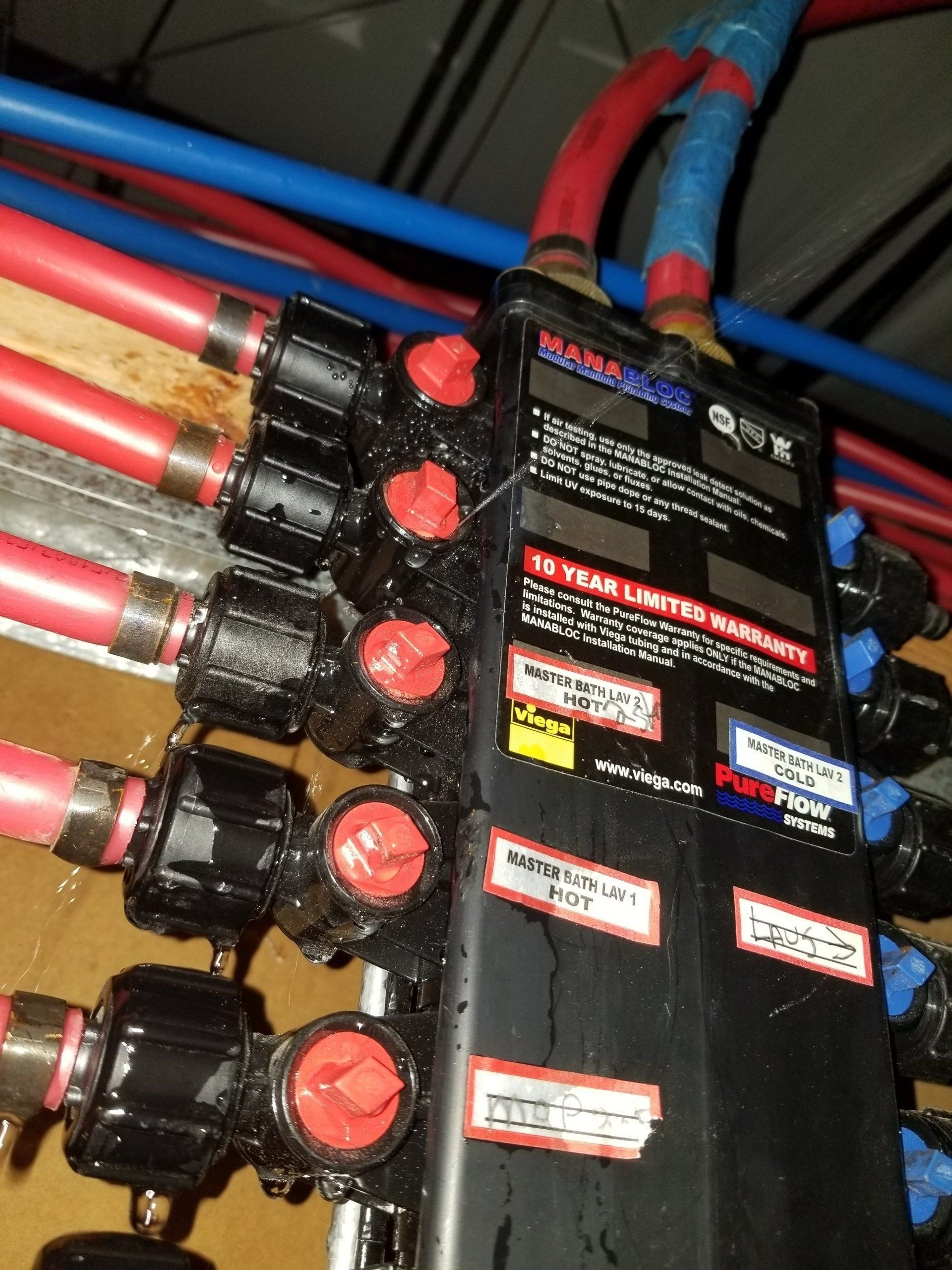 Electrical distribution panel with red-topped breakers and thick red, blue, and gold cables.