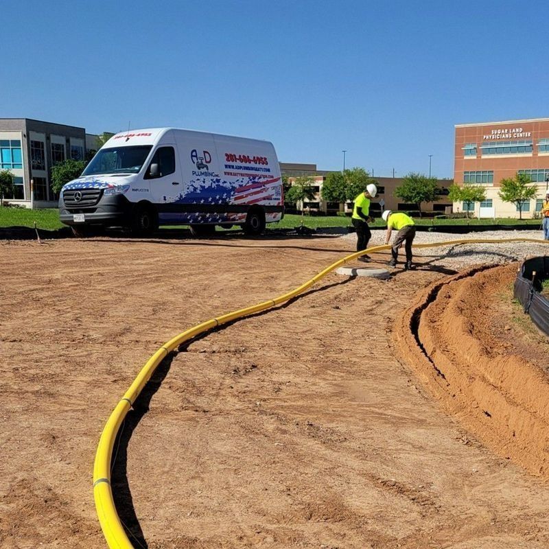 Workers laying yellow hose at a construction site beside a white service van under a blue sky
