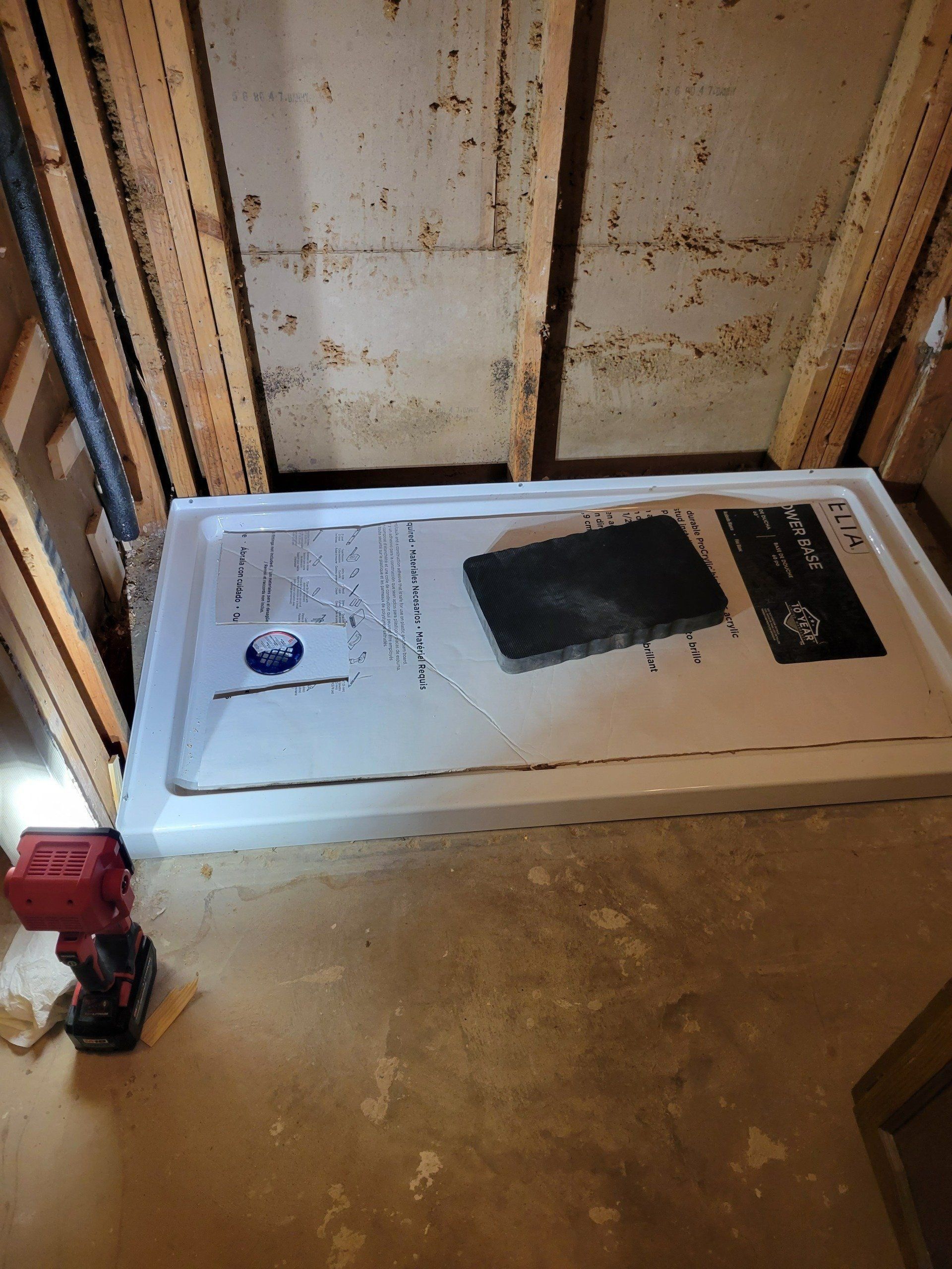 Old appliance set on a dusty floor inside unfinished walls, with a red power tool nearby.