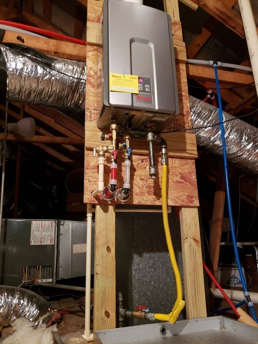 Water heater mounted in an attic, with exposed pipes, yellow gas line, and ductwork nearby