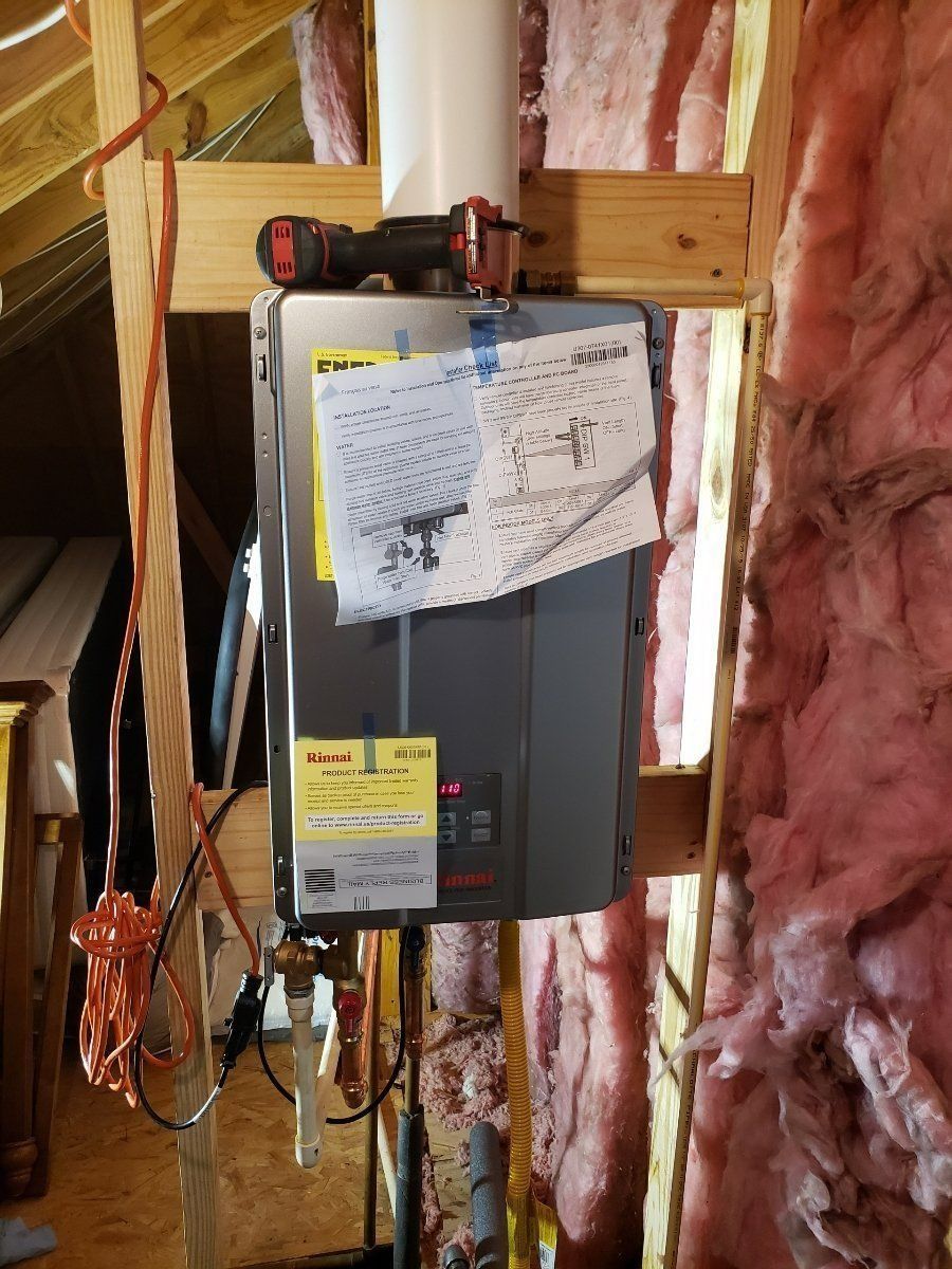 Gray electrical panel mounted in unfinished wall framing with pink insulation and a paper note clipped on top
