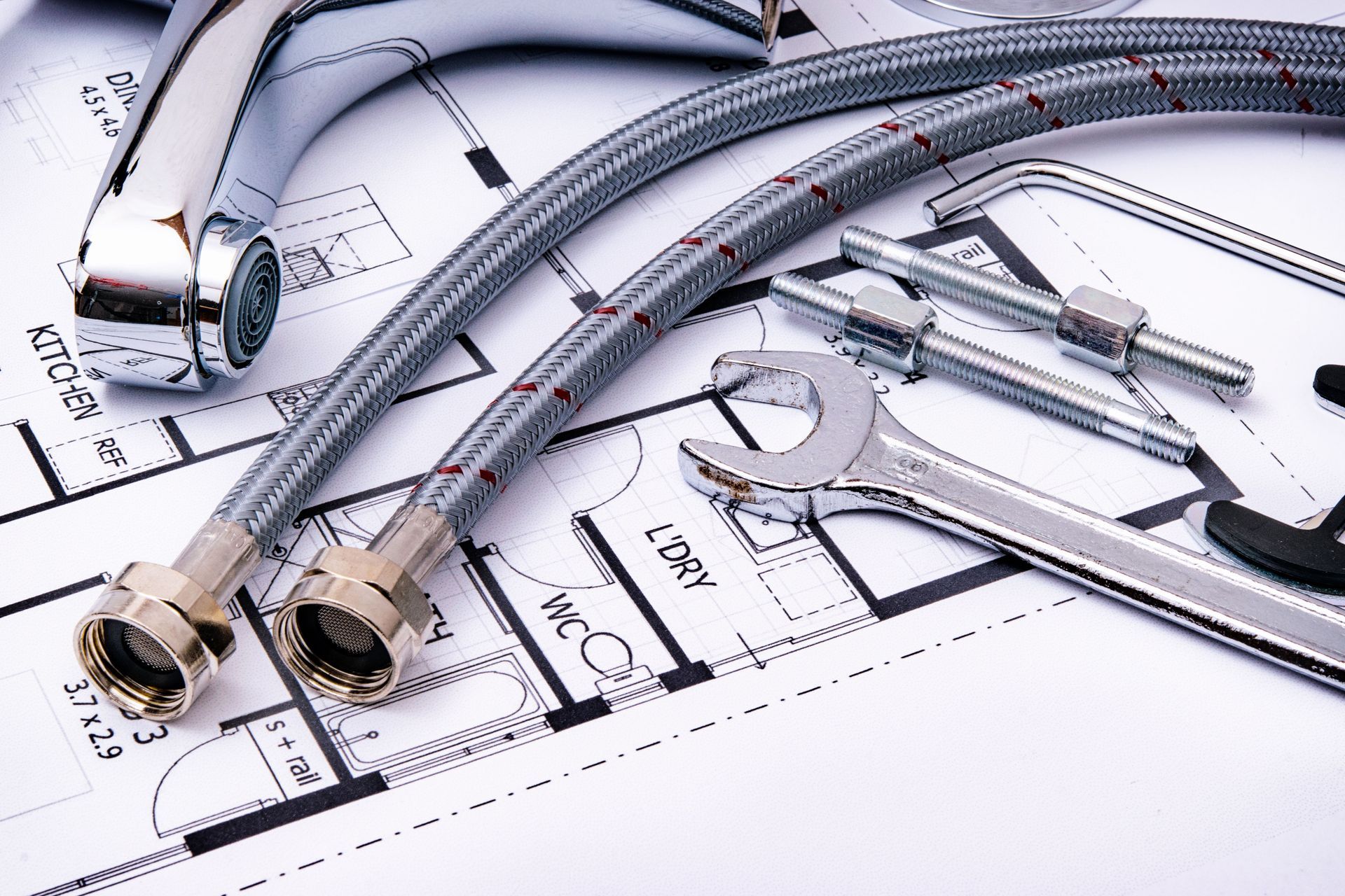 Chrome plumbing pipes and fittings laid on a technical blueprint drawing