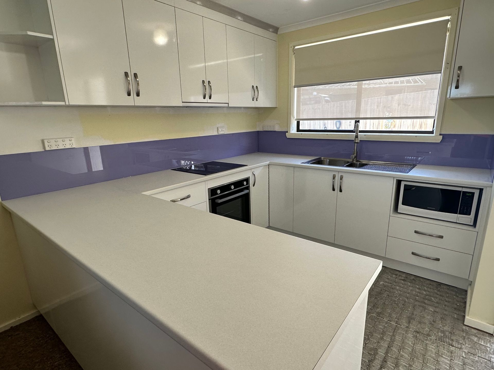 A kitchen with white cabinets and purple counter tops
