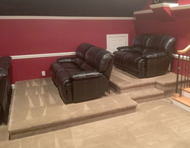 A living room with two black leather couches and stairs