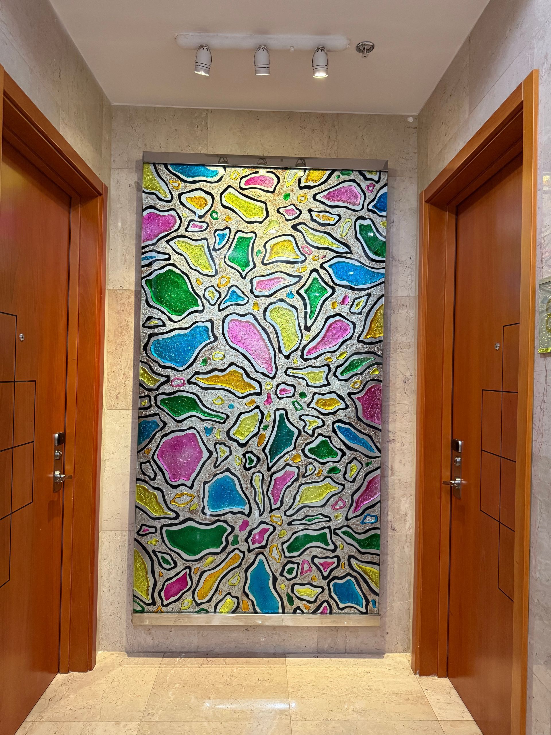 Colorful abstract art panel between two wooden doors in a hallway.
