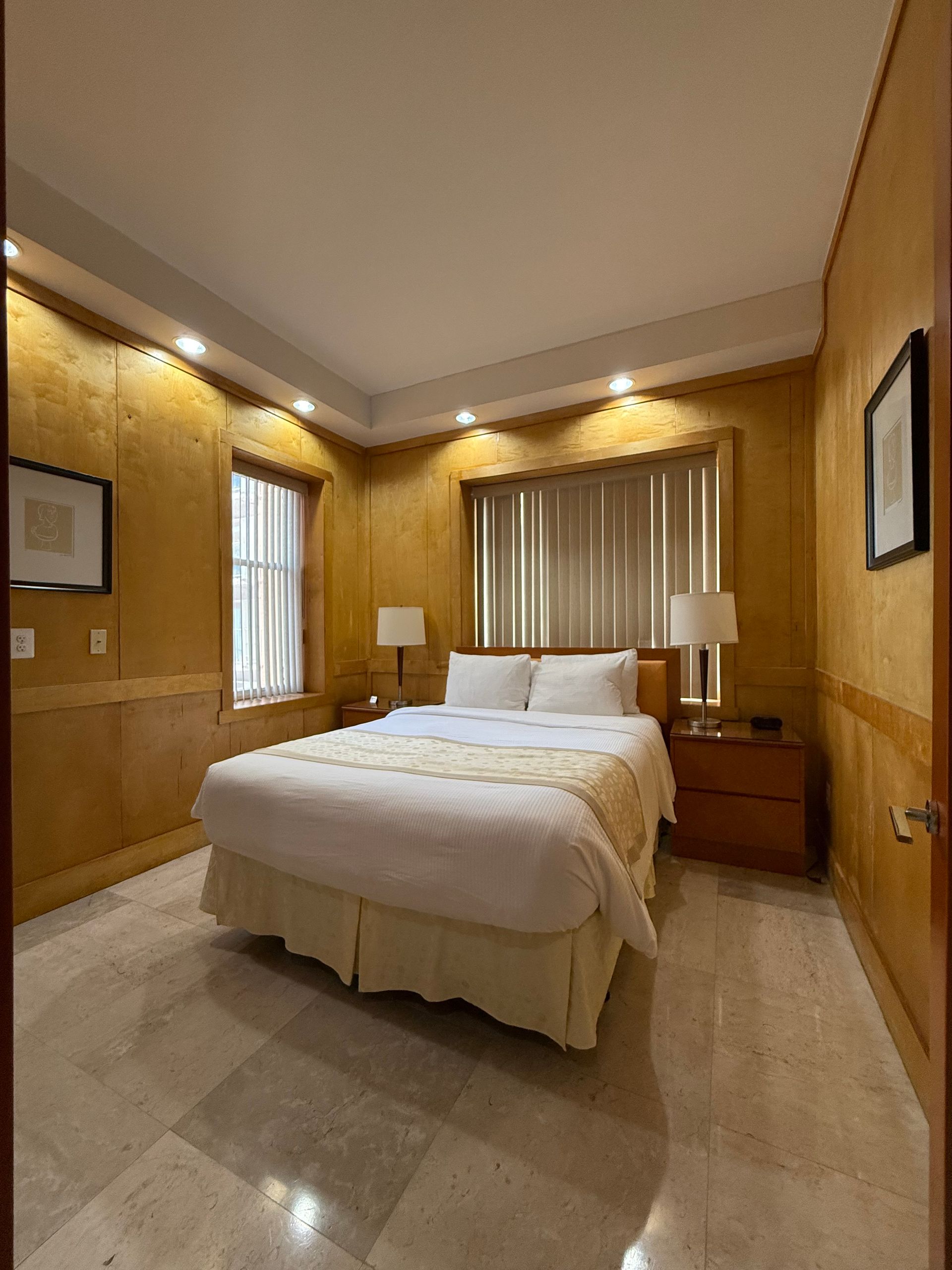 A hotel bedroom with a bed, nightstands, and beige walls.