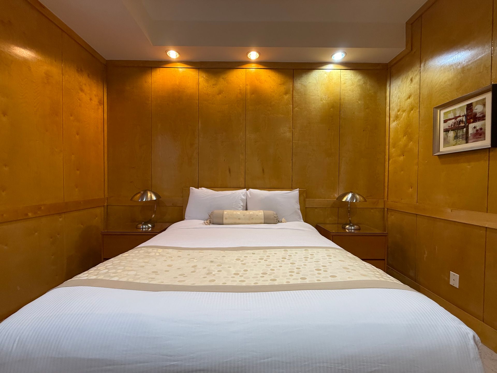 Bedroom with wood paneling, a bed with white bedding, and two bedside tables.
