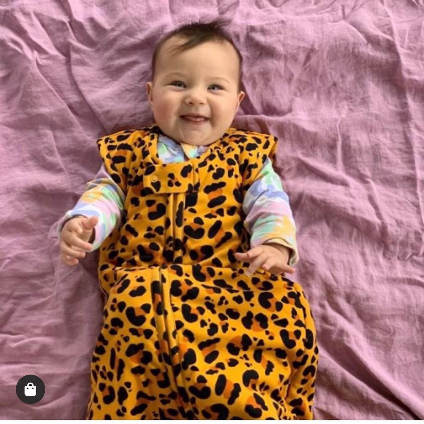 Smiling Baby in a Leopard Print Sleep Sack on a Pink Blanket — Decadence Gifts & Homewares in Emerald, QLD