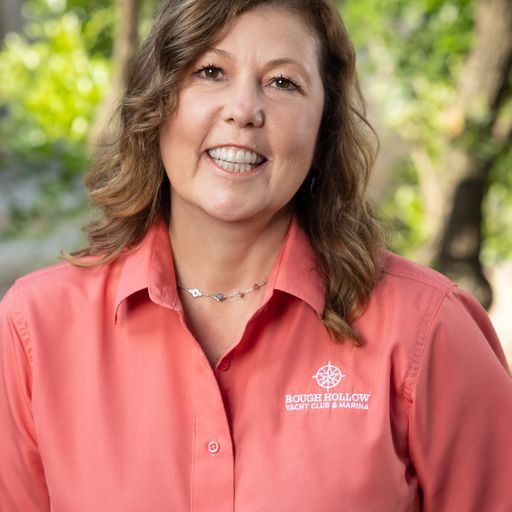 A smiling person wearing a coral-colored button-down shirt with a 