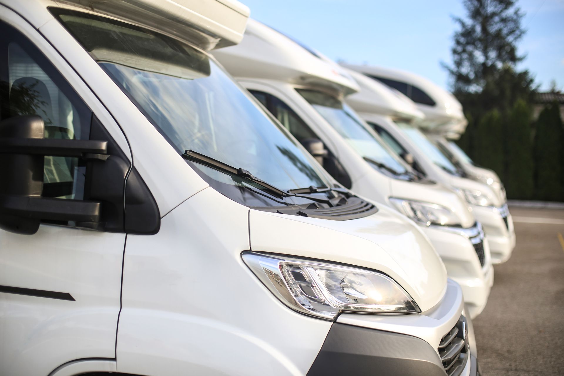 Row of white RVs parked outside.