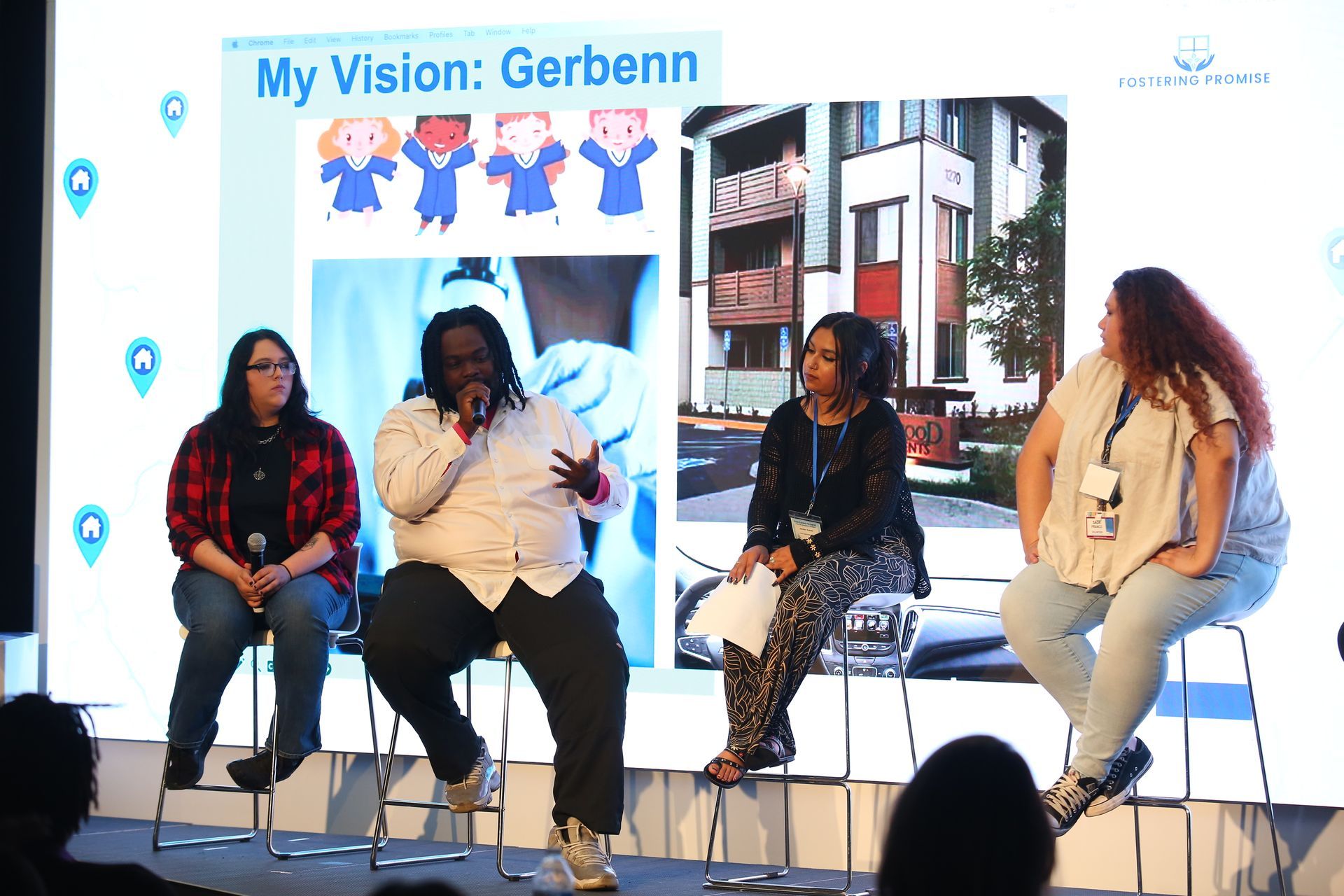 Four speakers sit on stools on a stage during a presentation with a “My Vision” backdrop.