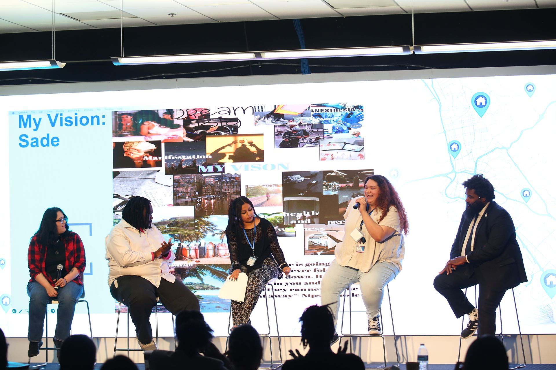 Panel discussion on stage with five seated speakers in front of a large screen reading “My Vision: Sade”