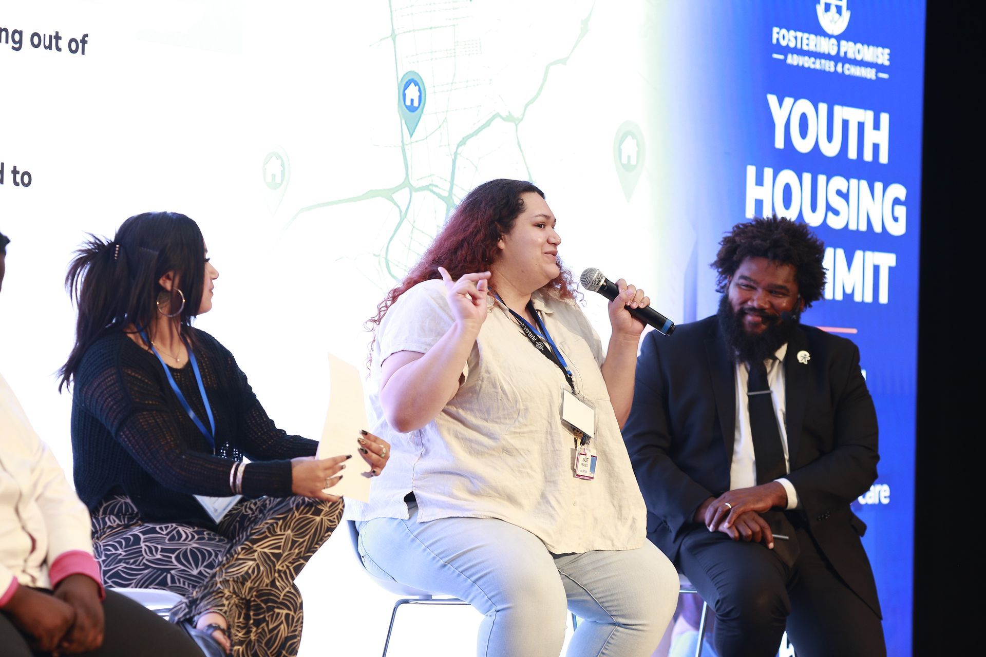 Panel discussion at a Youth Housing Summit, with speakers seated on stage and microphones in hand