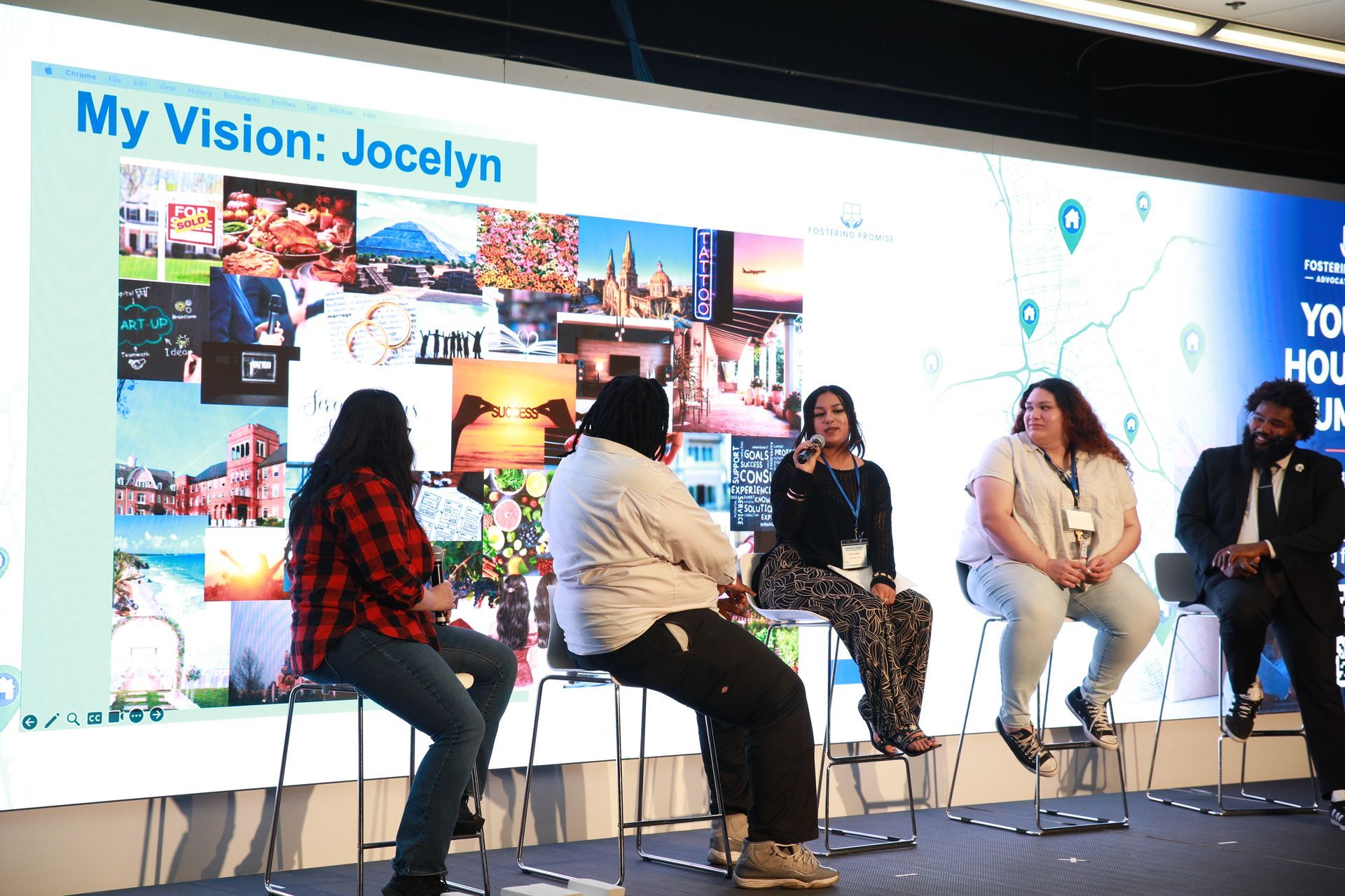 Panel discussion on stage with five speakers seated before a large presentation screen