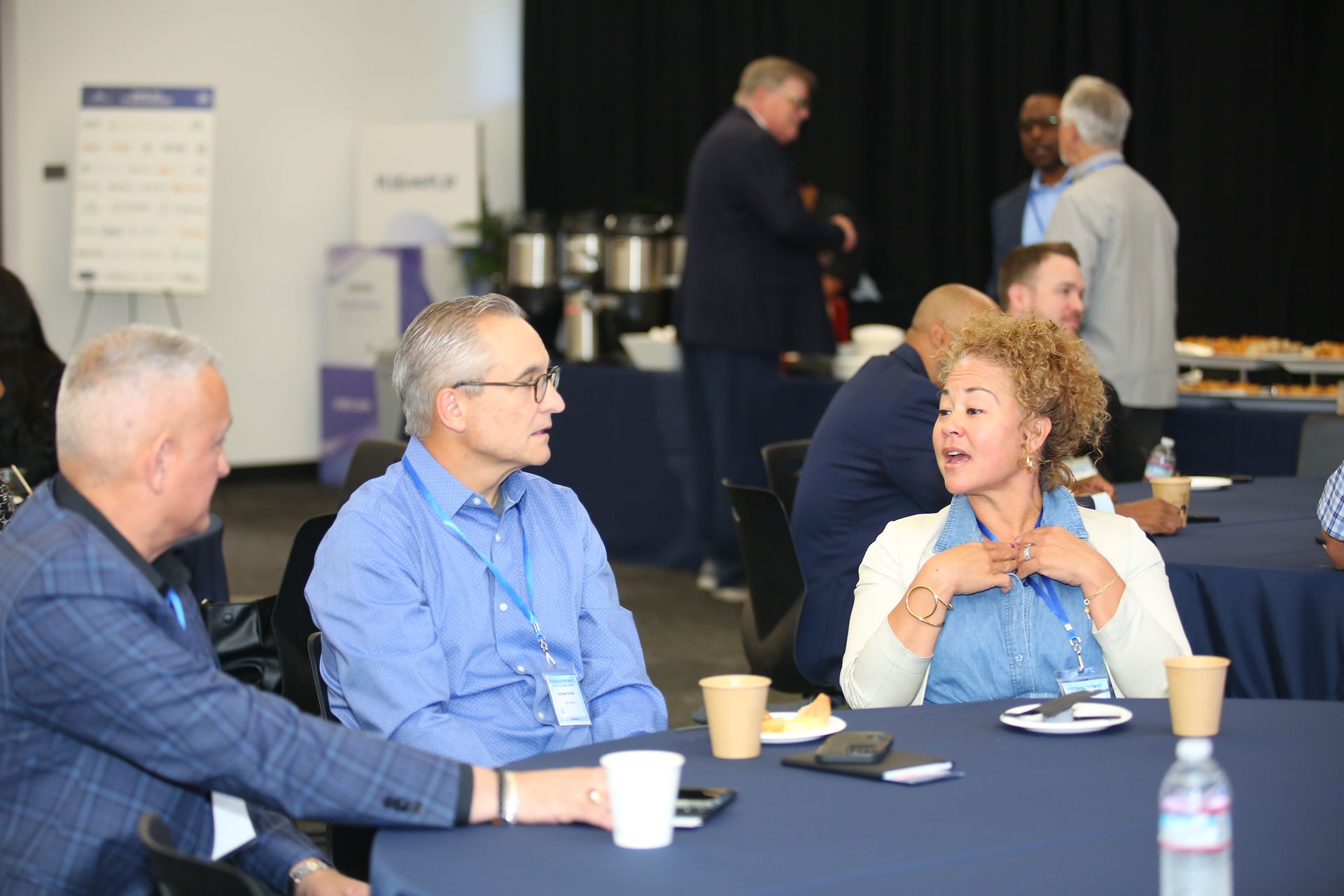 People seated at round tables chatting at a conference networking event