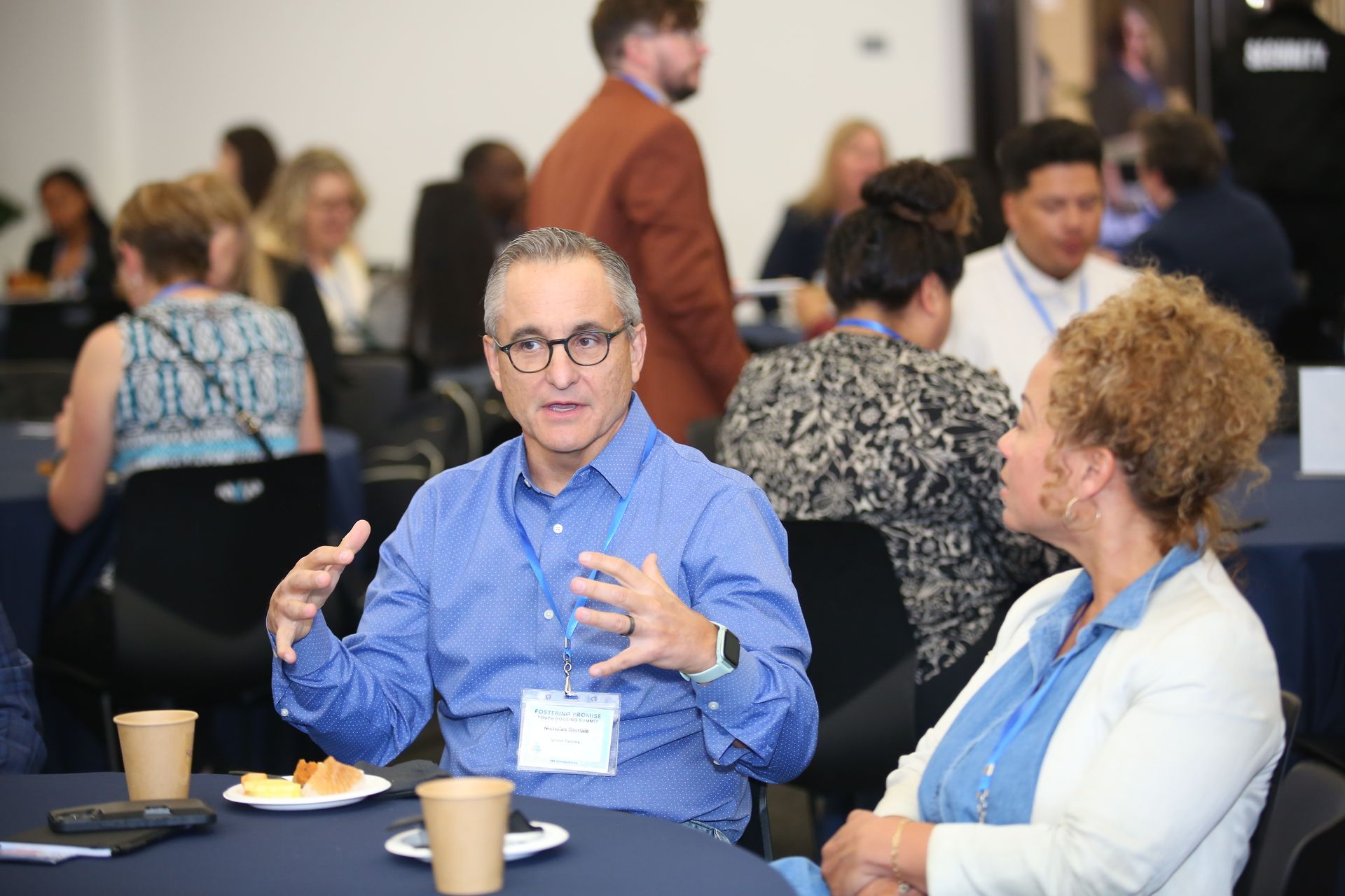 People talking at a conference table with coffee cups in a meeting room