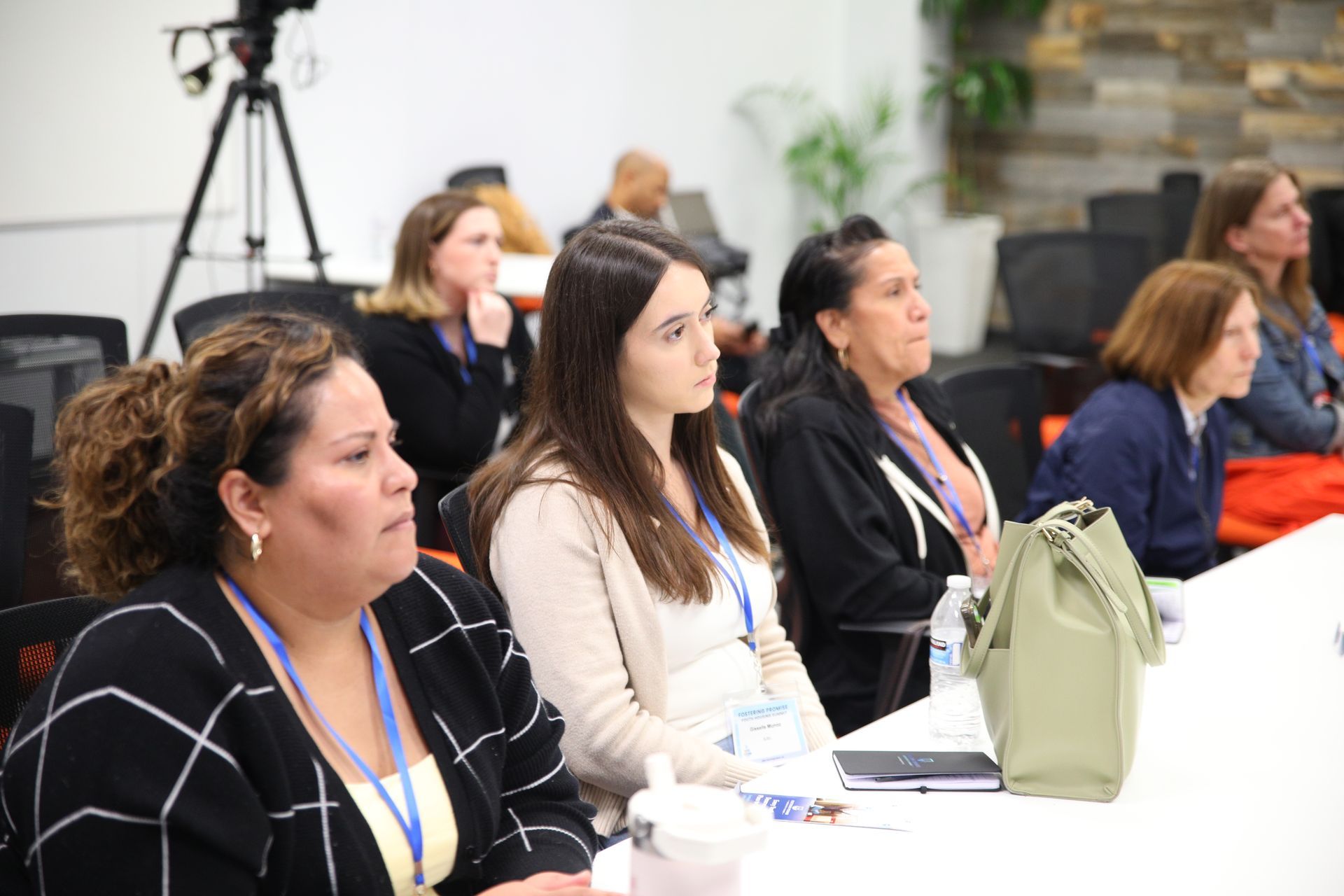 Audience seated at a conference table, listening attentively in a bright meeting room.