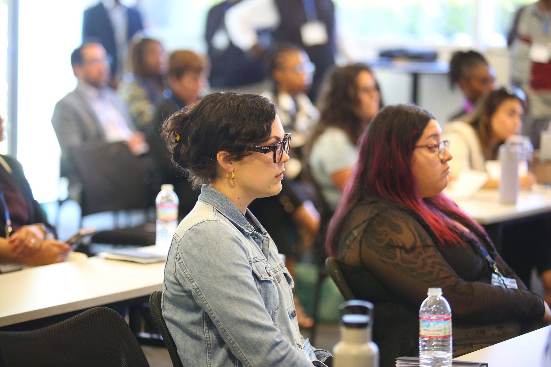 Audience seated in a conference room, listening attentively at a presentation