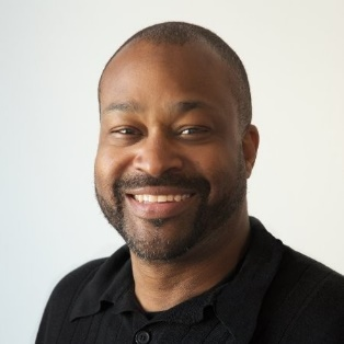 Smiling man in a black shirt against a light background