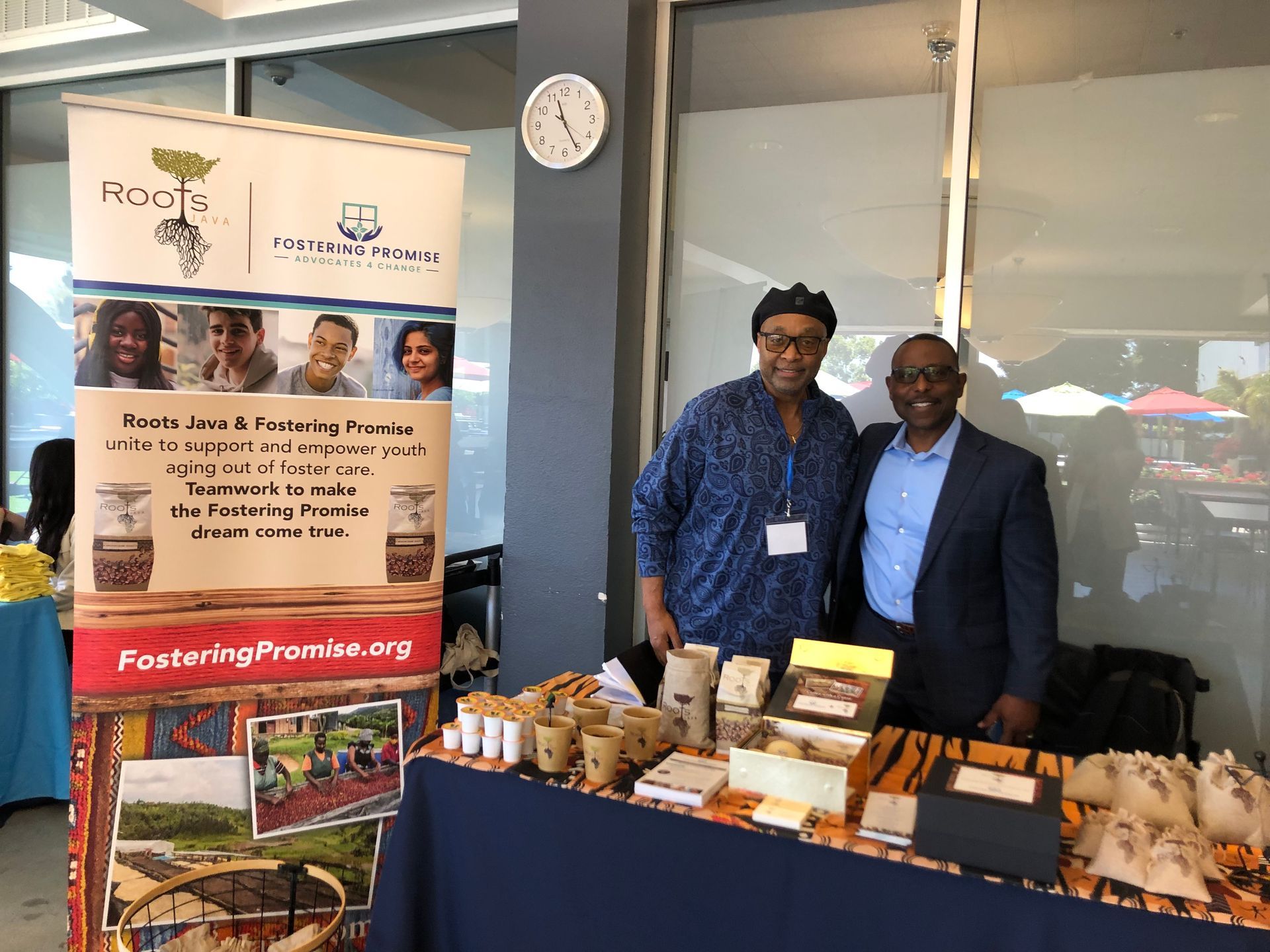 Two people at a table display of baked goods and brochures at a community booth