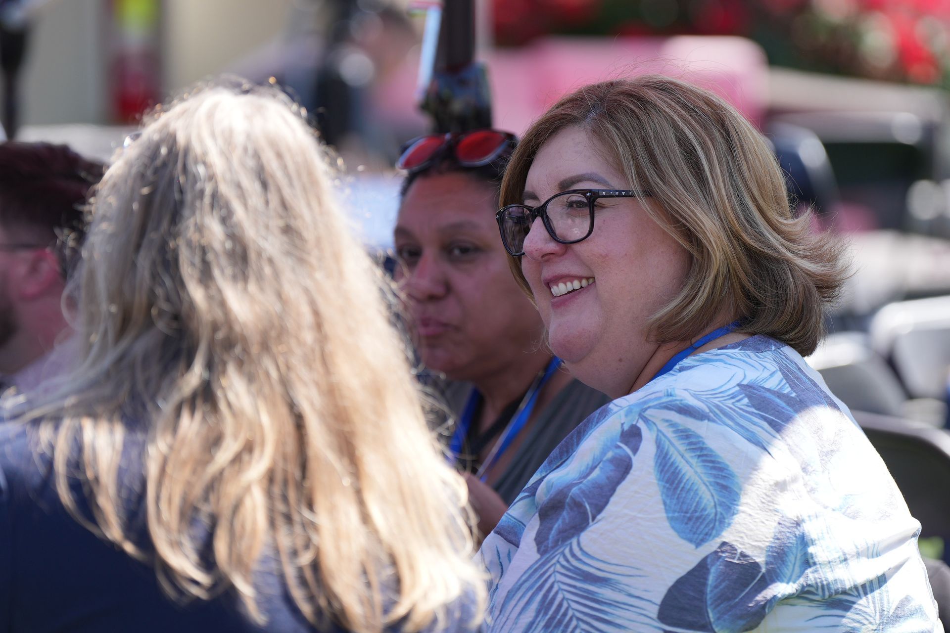 Smiling woman in glasses and a blue striped shirt at an outdoor gathering