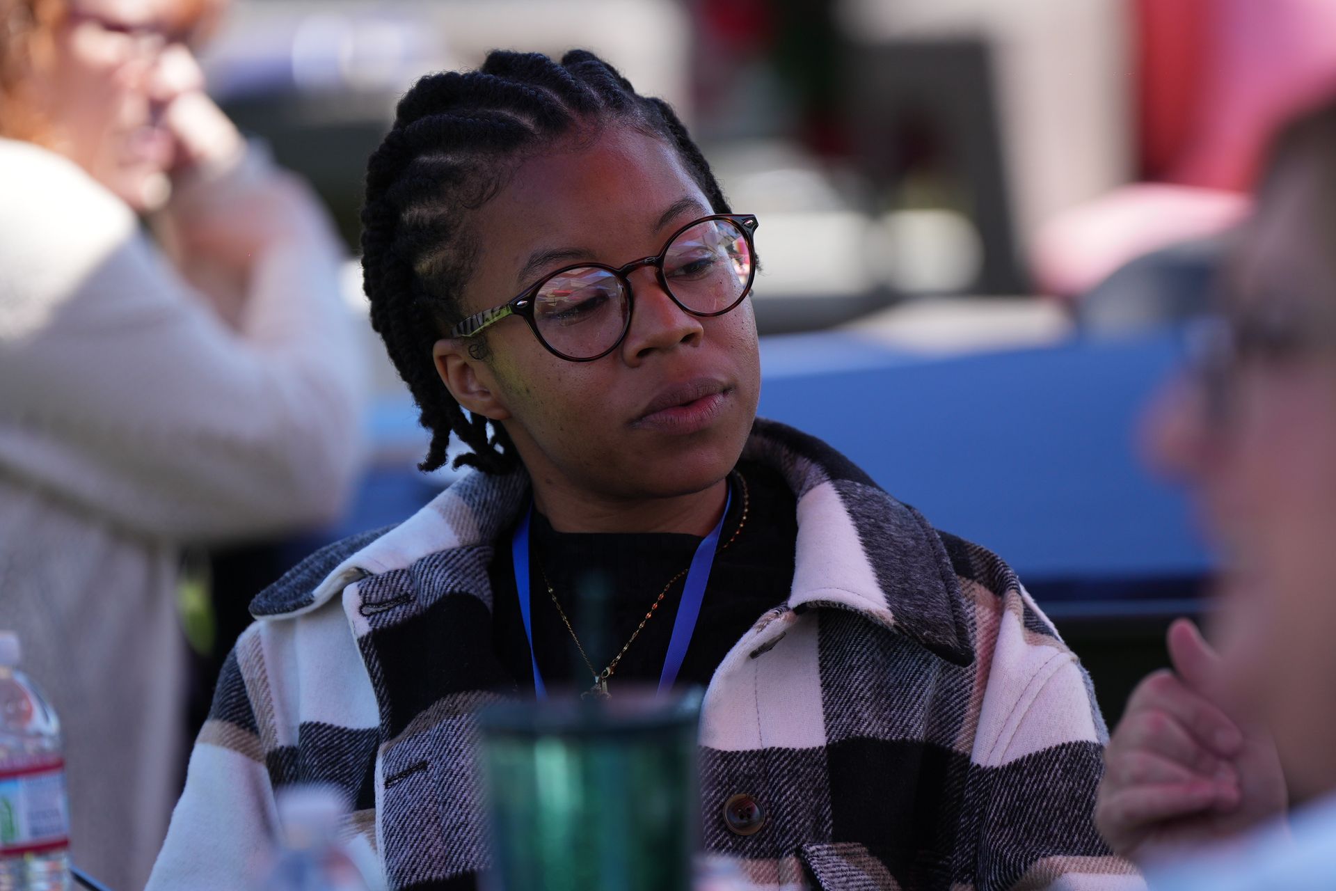 Person with glasses and braids sitting at a table, listening attentively in a meeting or discussion